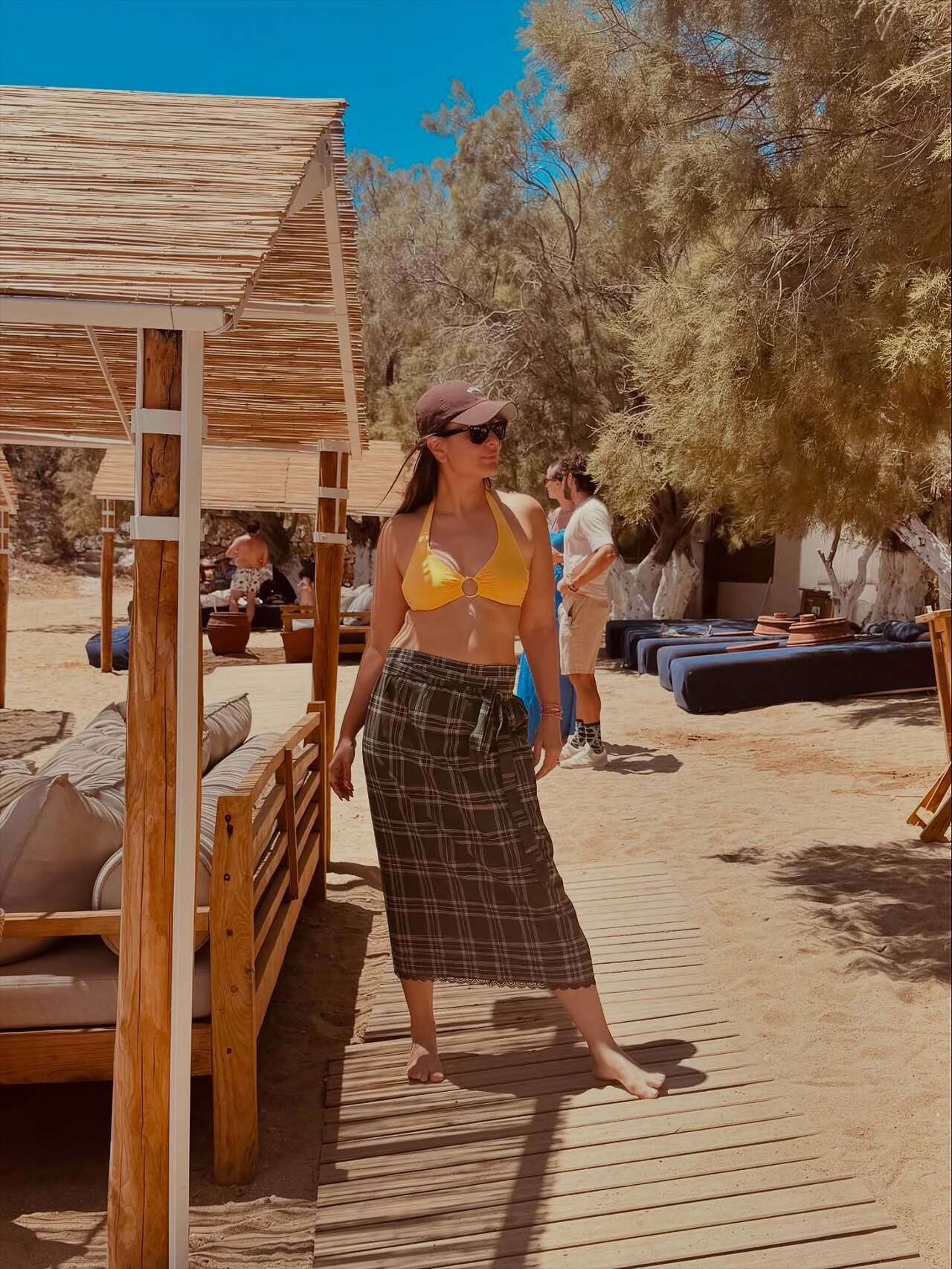 Kareena Kapoor’s viral bikini-lungi look from her Greece vacation blends desi sass with beach glam. She was seen enjoying her vacation in a bright yellow bikini top teamed up with a brown lungi-style skirt, sleek black sunglasses and a matching cap.